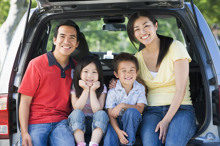 Insurance Quote - Happy Family With Young Kids Sitting In The Back Of Open Car Trunk